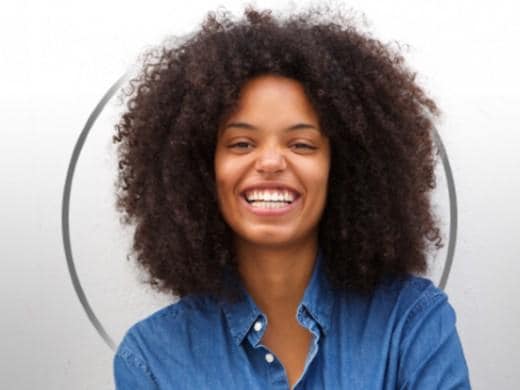 Mulher ruiva e jovem sorridente, a usar uma blusa verde, contente com o resultado do tratamento da vaginose bacteriana da Canesten